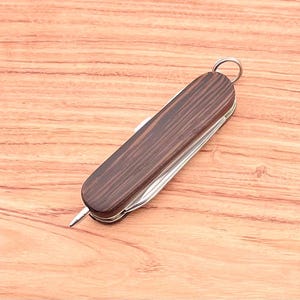 May include: A brown wood-handled pocket knife with a silver blade and a silver ring on the handle.
