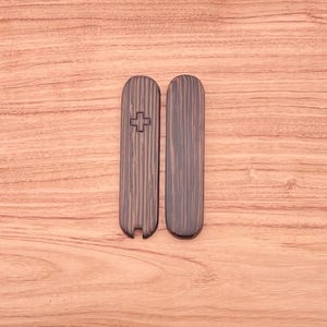 May include: Two wooden pieces with a cross carved into one of them. The pieces are dark brown with a wood grain pattern.