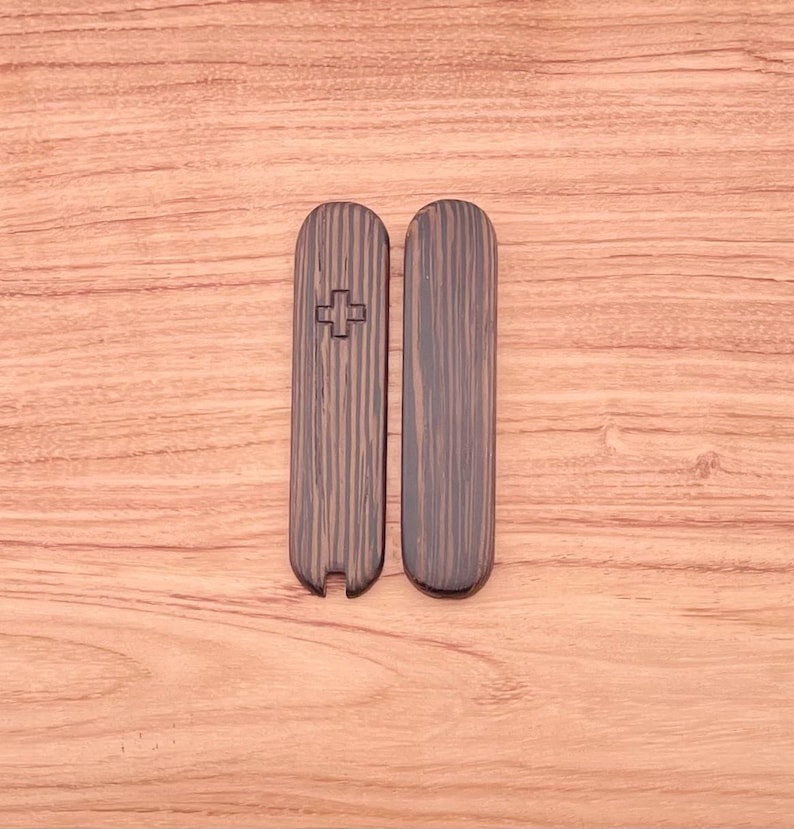 May include: Two wooden pieces with a cross carved into one of them. The pieces are dark brown with a wood grain pattern.