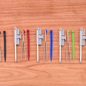 May include: A set of ten tools with different colored handles and tips. The tools are arranged in a row on a wooden surface.