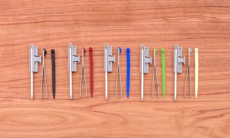 May include: A set of ten tools with different colored handles and tips. The tools are arranged in a row on a wooden surface.