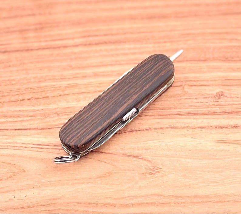 May include: A brown wood-handled pocket knife with a silver blade and a small silver loop on the end.