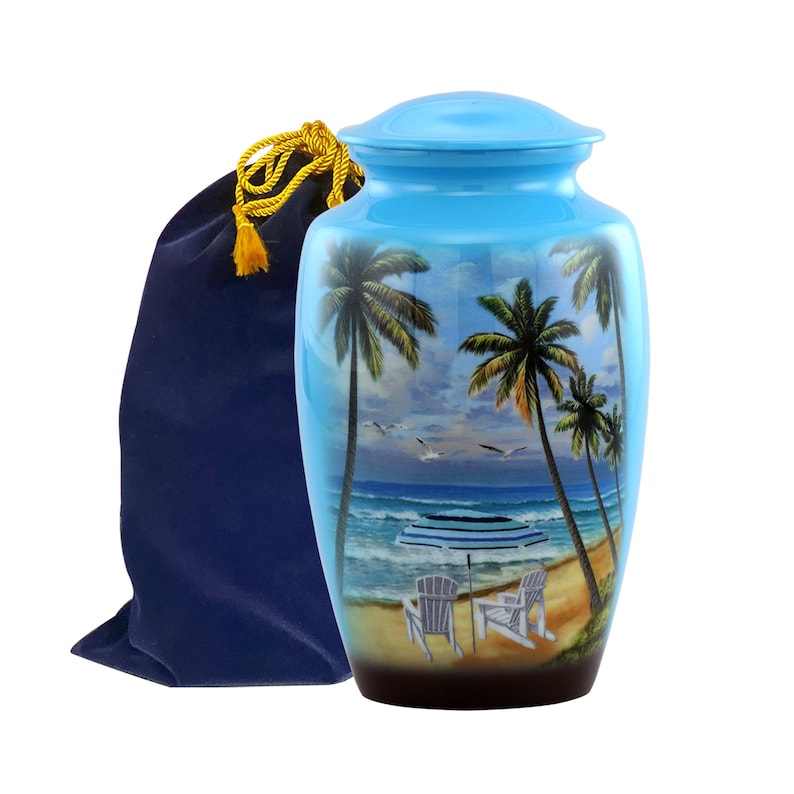 May include: A blue ceramic urn with a beach scene featuring palm trees, an umbrella, and two chairs. The urn comes with a blue velvet bag with a gold drawstring.