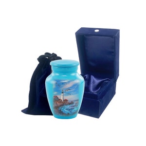 May include: A light blue cremation urn with a lighthouse and ocean scene. The urn comes with a blue velvet bag and box.