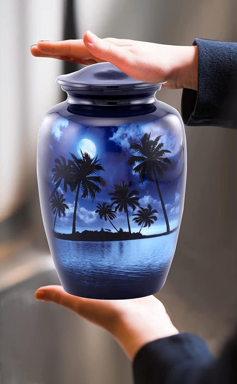 Puede incluir: Una urna de cer&aacute;mica azul con una silueta de palmeras y una luna llena sobre un fondo de cielo y agua azules.