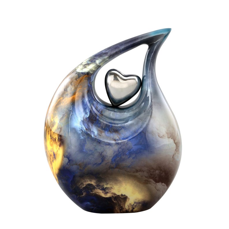 May include: A blue and gold ceramic urn with a silver heart cutout. The urn has a unique, abstract design.