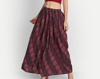 May include: A maroon crop top with short sleeves and a maroon maxi skirt with a geometric print. The skirt has a gathered waist.