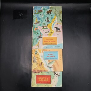 May include: Three vintage travel guides stacked on top of each other. The top guide is titled "Federation of Rhodesia and Nyasaland" with a map illustration. The middle guide is "Egypt and Syria." The bottom guide is "Kenya & Uganda."