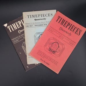Może przedstawiać: Trzy zabytkowe wydania magazynu Timepieces Quarterly opublikowane przez American Clock & Watch Foundation. Kolekcja zawiera ciemnobrązową, kremową i koralowo-czerwoną okładkę, każda z czarnym tekstem i centralnie umieszczonym logo.