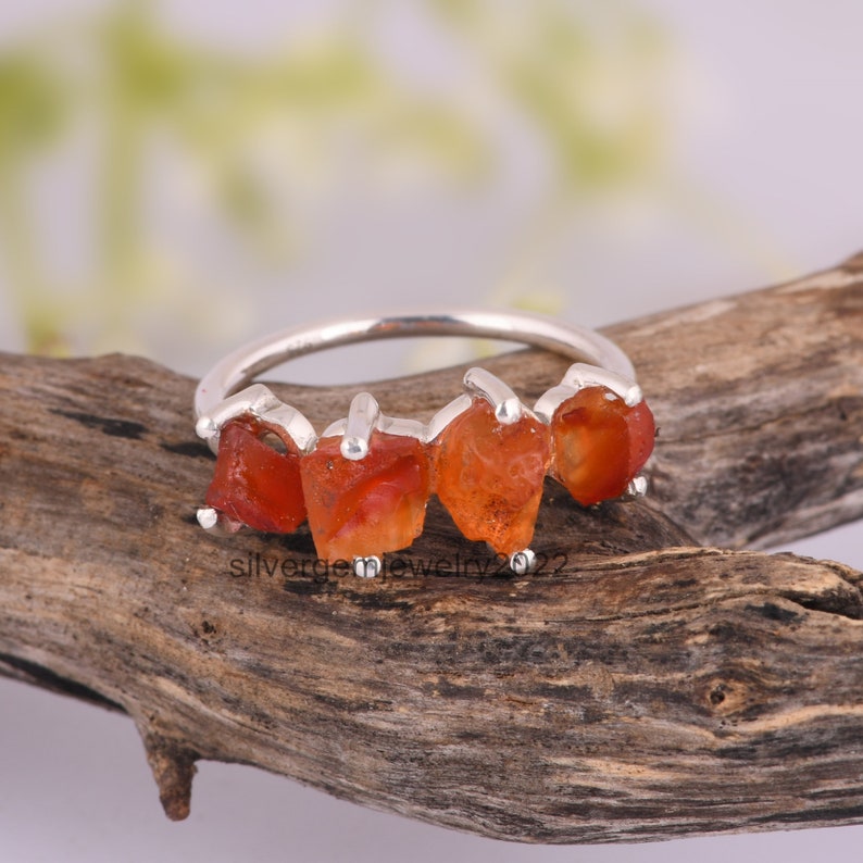 May include: A silver ring with five orange carnelian stones set in a row. The stones are rough and have a natural, raw look.