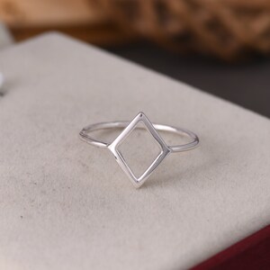 May include: A silver ring with a diamond-shaped open design.