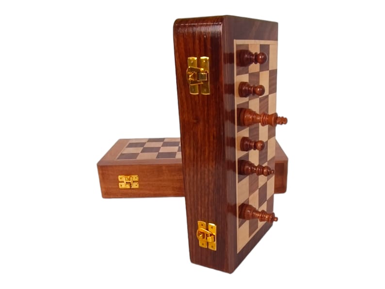 K&ouml;nnte beinhalten: Ein Schachspiel aus Holz mit dunkelbraunem Finish. Das Set enth&auml;lt ein Schachbrett, Schachfiguren und eine Aufbewahrungsbox. Das Schachbrett besteht aus hellen und dunklen Holzquadraten. Die Schachfiguren sind braun und beige.