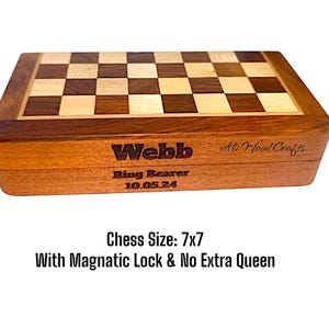 K&ouml;nnte beinhalten: Ein h&ouml;lzernes Schachspiel mit Schachbrettmuster. Die Box ist mit dem Namen "Webb", "Ring Bearer" und dem Datum "10.05.24" graviert. Das Schachspiel misst ca. 17.78 x 17.78 cm und hat einen Magnetverschluss.