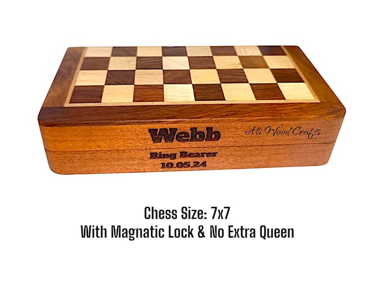 K&ouml;nnte beinhalten: Ein h&ouml;lzernes Schachspiel mit Schachbrettmuster. Die Box ist mit dem Namen "Webb", "Ring Bearer" und dem Datum "10.05.24" graviert. Das Schachspiel misst ca. 17.78 x 17.78 cm und hat einen Magnetverschluss.