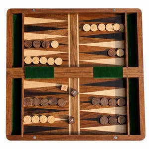 Könnte beinhalten: Ein Backgammon-Brett aus Holz mit hellen und dunklen Holz-Dreiecken. Das Brett hat grüne Filzeinsätze und ist mit hellen und dunklen Holzspielsteinen bestückt. Zwei Würfel sind auf dem Brett sichtbar und zeigen die Zahlen 5 und 3.
