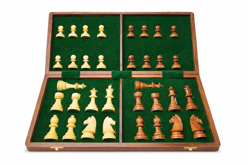 K&ouml;nnte beinhalten: Ein Schachspiel aus Holz mit gr&uuml;nem Filzinnenraum. Die Schachfiguren sind zweifarbig: hellbeige und braun. Das Set ist ge&ouml;ffnet und zeigt alle Figuren in ihren Ausgangspositionen.