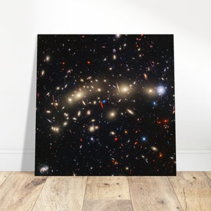 Puede incluir: Una fotografía en blanco y negro de una vasta extensión del espacio llena de innumerables estrellas y galaxias. La imagen muestra un cúmulo de galaxias, algunas de las cuales aparecen como brillantes rayas de luz alargadas.