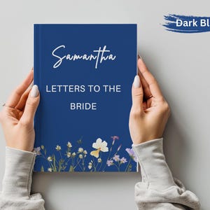 May include: A dark blue journal titled "Samantha Letters to the Bride" with floral accents. The cover features the name "Samantha" in elegant script. The journal is held by two hands.