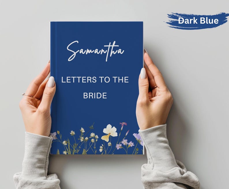 May include: A dark blue journal titled "Samantha Letters to the Bride" with floral accents. The cover features the name "Samantha" in elegant script. The journal is held by two hands.