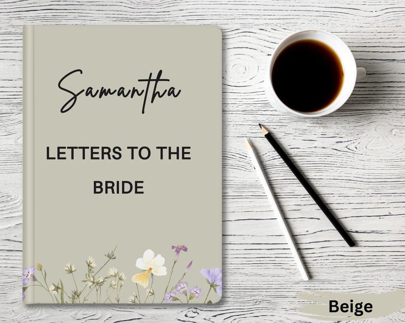 May include: Beige journal with the text 'Samantha Letters to the Bride' and floral illustrations. The journal is on a white wood background.
