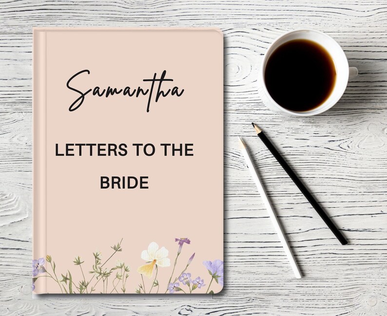 May include: A pink journal with the text 'Samantha' and 'Letters to the Bride' on the front cover. The journal has a floral design at the bottom of the cover.