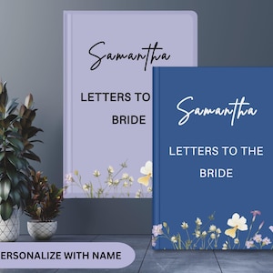 May include: Two personalized notebooks, one lavender and one navy blue, with the name "Samantha" in script. The text "Letters to the Bride" is printed below. Floral accents adorn the bottom of each notebook. The bottom of the image reads "Personalize with Name."