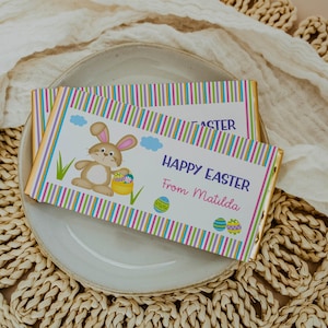 May include: A colorful striped chocolate bar wrapper with a cartoon bunny holding a basket of Easter eggs. The wrapper says "Happy Easter from Matilda".
