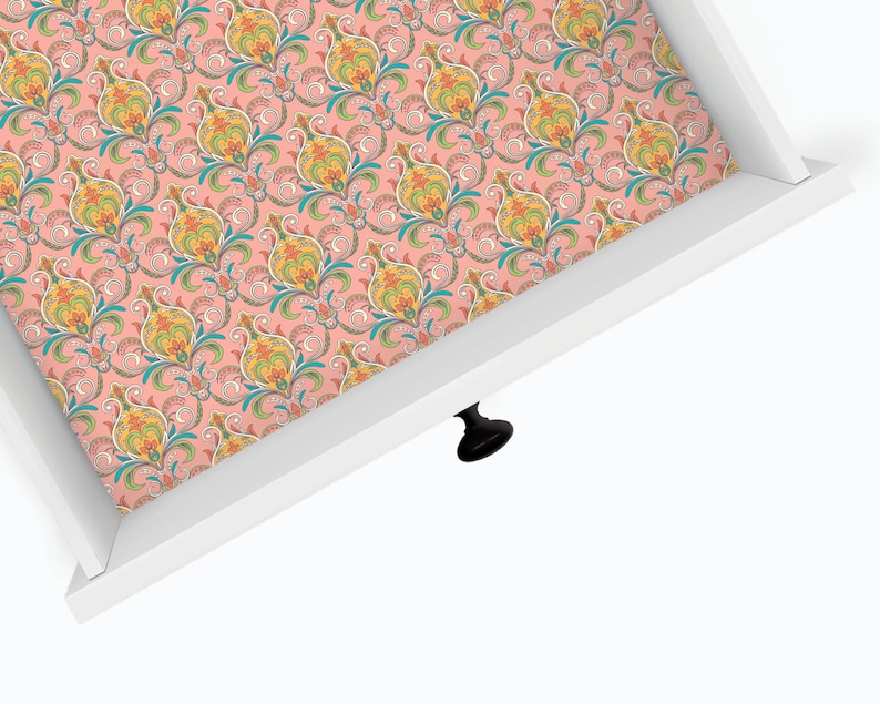 May include: A white drawer with a pink and colorful floral patterned liner. The drawer has a black knob.