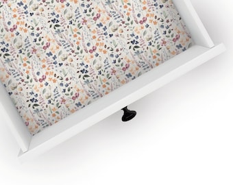 May include: A white drawer with a floral pattern liner. The drawer has a black knob.