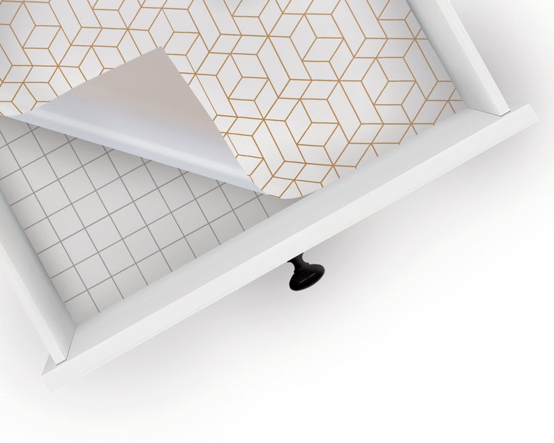 May include: A white drawer with a gold geometric patterned liner being pulled open. The liner is partially peeled back to reveal the white drawer bottom.