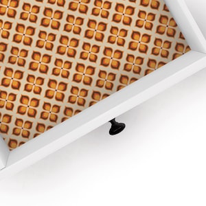 May include: White drawer with a black knob and a retro patterned liner in shades of orange, brown, and white.