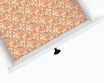 May include: A white drawer with a floral pattern liner. The drawer has a black knob.