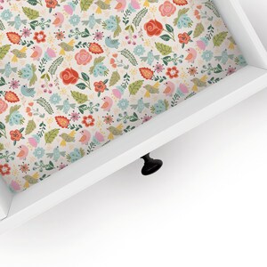May include: A white drawer with a floral pattern liner. The liner features pink, red, blue, and green flowers, leaves, and birds.