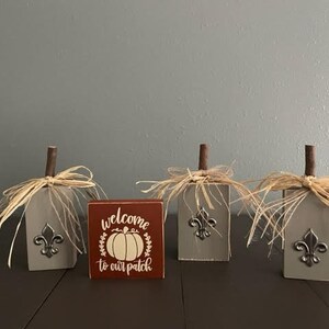 Small barnwood gray wood pumpkin trio with wooden stems, metal fleur de lis and raffia