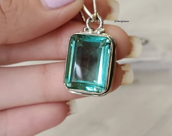 May include: A silver pendant with a large, light blue, rectangular gemstone. The pendant is on a silver chain.