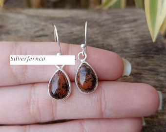 May include: A pair of silver dangle earrings with teardrop-shaped red and black jasper stones.