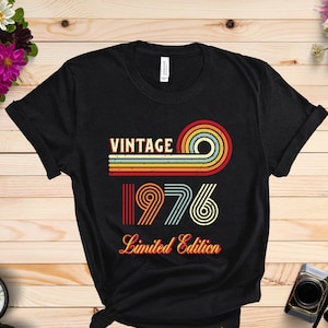 May include: Black t-shirt with a vintage 1976 design in rainbow colors. The text "Vintage" and "Limited Edition" is printed on the shirt.