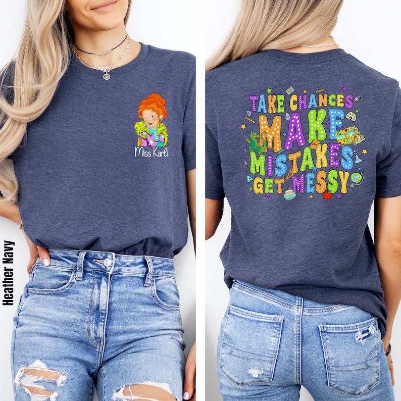 May include: A heather navy blue t-shirt with a cartoon teacher and the text "Miss Karl" on the front. The back of the shirt has the text "Take Chances Make Mistakes Get Messy" with colorful illustrations of school supplies.