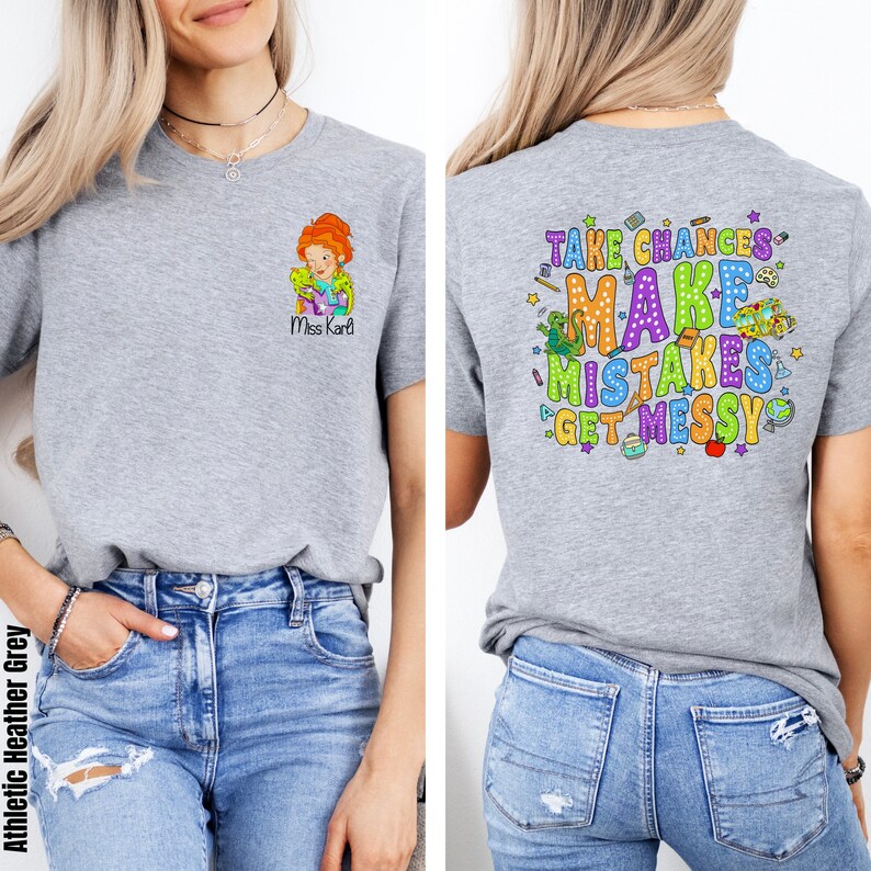 May include: A heather grey t-shirt with a cartoon teacher and the text "Miss Karl" on the front. The back of the shirt has the text "Take Chances Make Mistakes Get Messy" with colorful illustrations of school supplies and a dinosaur.