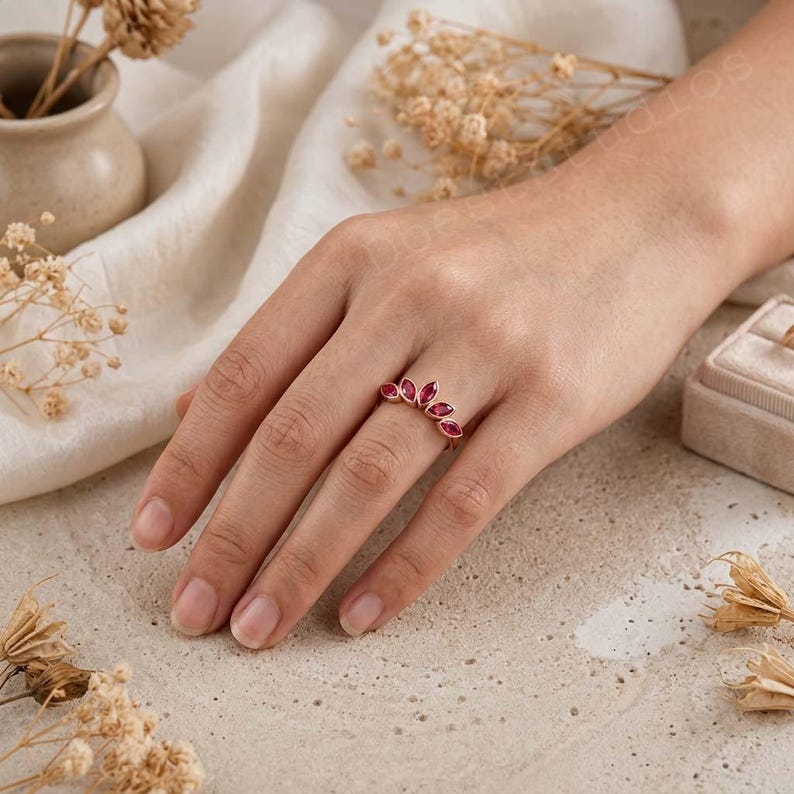 Peut inclure: Une bague en or rose orn&eacute;e de cinq pierres pr&eacute;cieuses roses taille marquise dispos&eacute;es en &eacute;ventail incurv&eacute;. L'anneau est fin et m&eacute;tallique, avec une finition polie qui met en valeur la teinte rose vive et profonde des pierres facett&eacute;es.