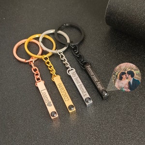 Peut inclure: Quatre porte-clés personnalisés avec des messages gravés différents. Les porte-clés sont en métal et ont une finition noire, argentée, dorée et or rose. Les messages sur les porte-clés sont "Forever your Angel", "My best friend x", "04/02/2022", et "Loann".