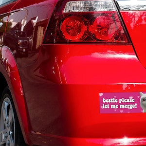 Peut inclure: Arri&egrave;re d'une voiture rouge avec un autocollant sur le pare-chocs. L'autocollant dit "bestie please let me merge!" et pr&eacute;sente un m&egrave;me d'un chat blanc en pleurs. Les feux arri&egrave;re de la voiture sont &eacute;galement visibles.