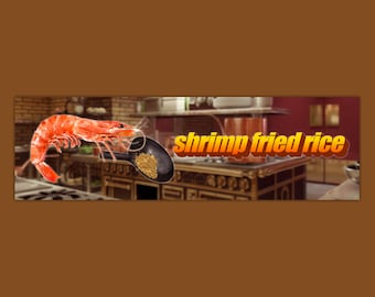 May include: A large, cooked shrimp sits on a black pan with a scoop of fried rice. The text "shrimp fried rice" is in yellow and orange letters on a white background.