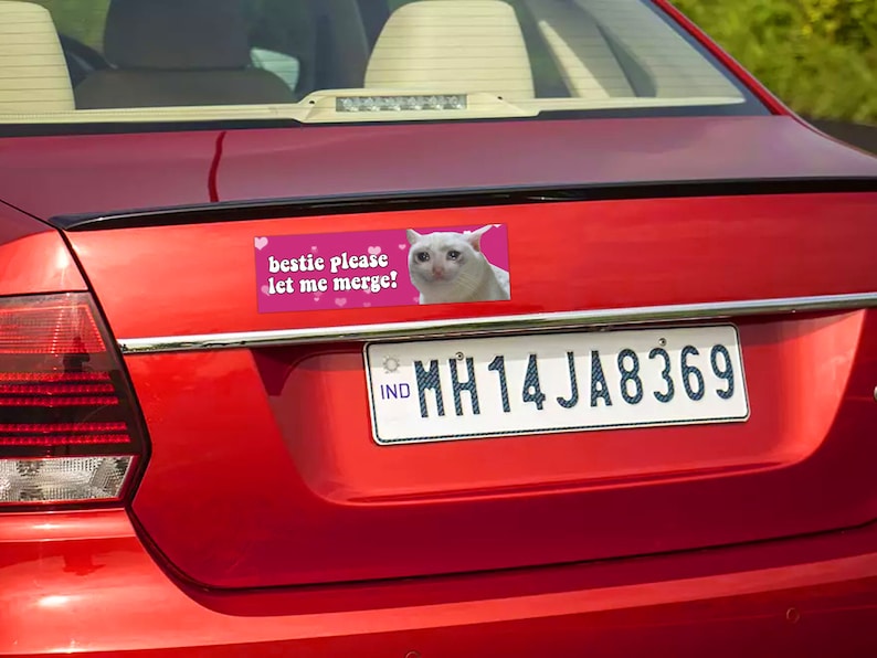 Peut inclure: Arri&egrave;re d'une voiture rouge avec un autocollant. L'autocollant dit "bestic please let me merge!" et pr&eacute;sente un m&egrave;me d'un chat blanc qui pleure. La voiture a une plaque d'immatriculation avec le texte "MH14 JA8369".