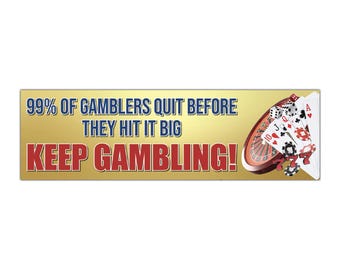 May include: A rectangular sign with a gold background and the text "99% OF GAMBLERS QUIT BEFORE THEY HIT IT BIG KEEP GAMBLING!" in blue and red. A roulette wheel, playing cards, and poker chips are on the right.