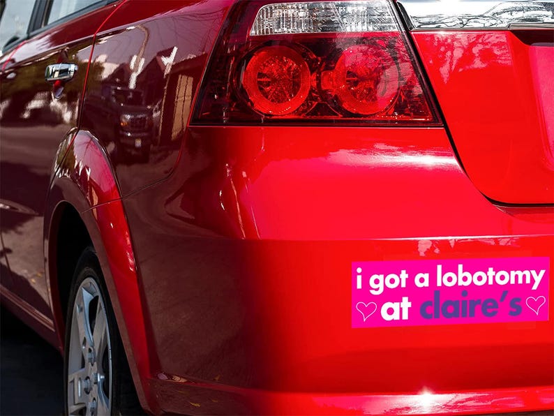 May include: A red car with a bumper sticker that reads "i got a lobotomy at claire's" with pink hearts on either side of the text.