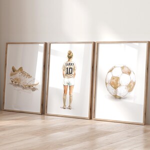 May include: Three framed watercolor illustrations: a white soccer cleat, a female soccer player wearing a white jersey with the name "Sammy" and the number "10" on the back, and a brown and white soccer ball.