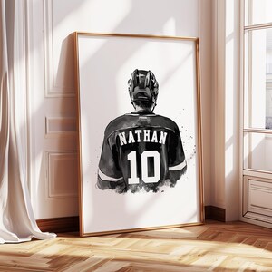 May include: Framed art print featuring a hockey player from the back, wearing a black jersey with the name "NATHAN" and the number "10" in white. The player is wearing a black helmet. The artwork is in black and white.