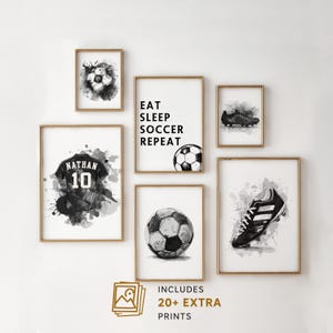 May include: A collection of framed black and white soccer-themed art prints. The prints include soccer balls, cleats, a jersey with the name "Nathan" and the number "10", and the phrase "Eat Sleep Soccer Repeat". The prints are in gold frames.