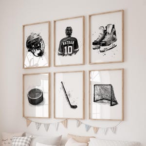 May include: Six framed black and white watercolor prints of hockey equipment and a player. The prints include a helmet, jersey with the name "Nathan" and the number 10, skates, a puck, a hockey stick, and a net.